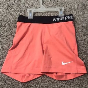 Peach Nike Pros 5” with a black band.